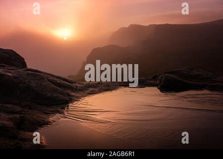 UK weather: stunning weather conditions at the famous Cow and Calf Rocks at sunrise with a temperature inversion causing fog in the valley but sunshine higher up. Ilkley Moor, West Yorkshire Stock Photo