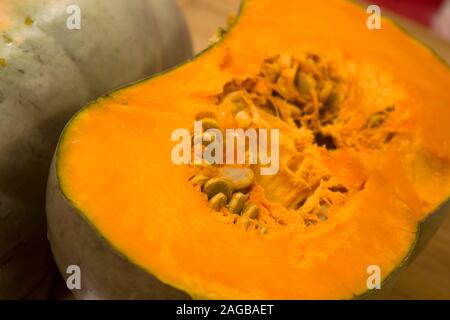 An orange pumpkin cut in half on the kitchen top. Stock Photo