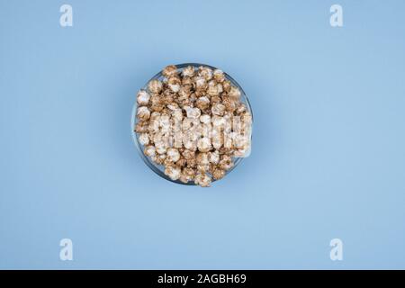 Caramel sweet popcorn bowl isolated on pink background top view. Frame composition with copy space. Stock Photo