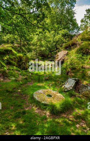 Abandoned completed millstones stacked at a small quarry in Lawrence Field above Padley Gorge near Grindleford, Peak District Stock Photo