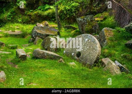 Abandoned completed millstones stacked at a small quarry in Lawrence Field above Padley Gorge near Grindleford, Peak District Stock Photo