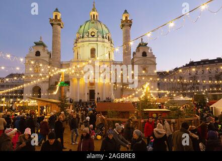 Vienna christmas market - people at the market in Karlsplatz in front of St Charles church (Karlskirche), at sunset, Vienna Austria Europe Stock Photo