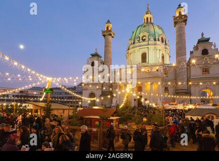 Vienna christmas market - people at the market in Karlsplatz in front of St Charles church (Karlskirche), at sunset, Vienna Austria Europe Stock Photo