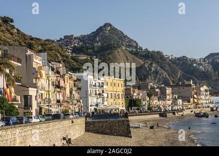 View of Taormina from Naxos with buildings, sea, rocks and blue sky Stock Photo