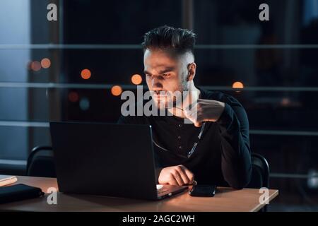 Stylish young businessman works alone in the office at nightime Stock Photo