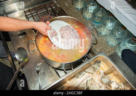 Steaming hot Greek famous healthy traditional homemade seafood soup with fresh grouper, saltwater mussels, shrimps, mini tomatoes, celery and onions. Stock Photo