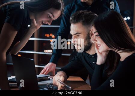 Focused photo. Team of young business people works on their project at night time in the office Stock Photo