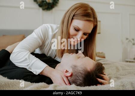 Pretty loving couple is luxuriating in bed together. They are hugging and smiling Stock Photo