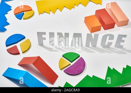 finance inscription near multicolor blocks and pie charts with shadow on white background Stock Photo