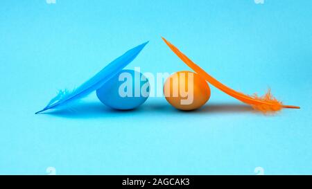 Easter multi-colored eggs and feathers on blue background. Stock Photo
