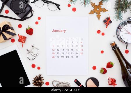 january calendar page, digital camera, alarm clock, digital tablet, champagne bottle, cosmetics, glasses, fir branch, fresh strawberry, christmas baub Stock Photo