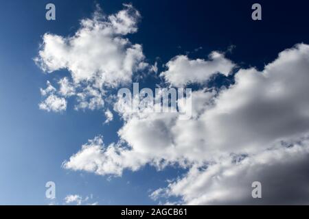 Dark evening sky with white clouds. Twilight blue sky with puffy cumulus clouds, heavenly landscape. Background wallpaper backdrop texture. Empty sky, Stock Photo