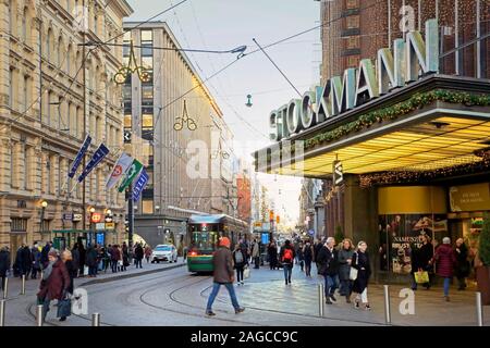 Aleksanterinkatu with a tram departing and Stockmann flagship store with busy Christmas shoppers in December. Helsinki, Finland. December 3, 2019. Stock Photo