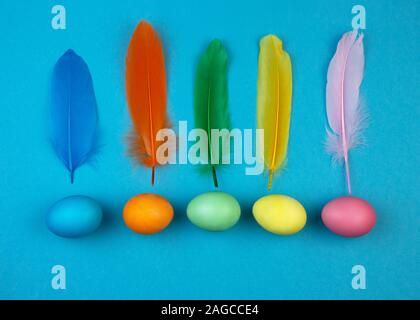 Easter multi-colored eggs and feathers on blue background. Stock Photo