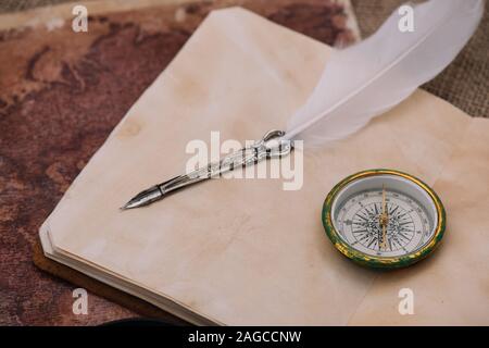 nib and compass on blank page of copy book on old world map Stock Photo