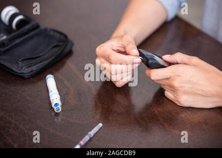 selective focus of woman holding glucose monitor while doing blood test at home Stock Photo