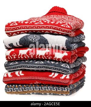 Stack of folded knitted Christmas turtleneck sweaters or pullovers with nordic ornament isolated on white background Stock Photo