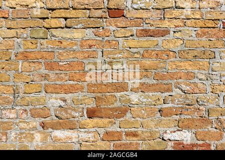 Background of an old weathered wall with yellow, orange and brown-red bricks Stock Photo