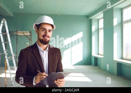 Foreman bearded man in a white helmet in a room at a construction site Stock Photo