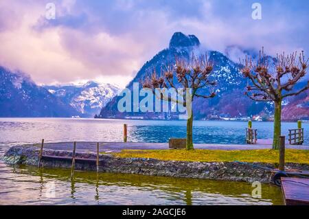 The rainy evening on Traunsee lake with a view on rippled water surface and huge Alpine mountain range, stretching along its bank and covered with hea Stock Photo