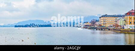 GMUNDEN, AUSTRIA - FEBRUARY 22, 2019: The morning walk along the foggy Traun lake (Traunsee) with a view on Alps in clouds, city center, floating swan Stock Photo