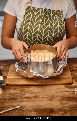 Cropped view of confectioner doing form of cake on chopping board Stock Photo
