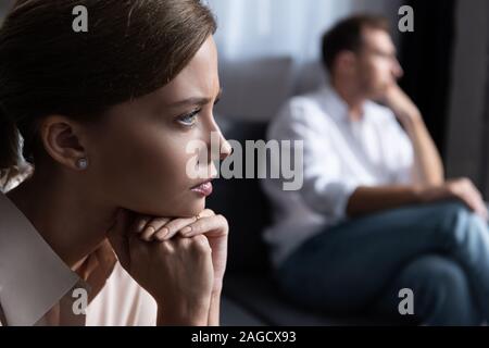 upset pensive young woman and husband sitting on sofa Stock Photo