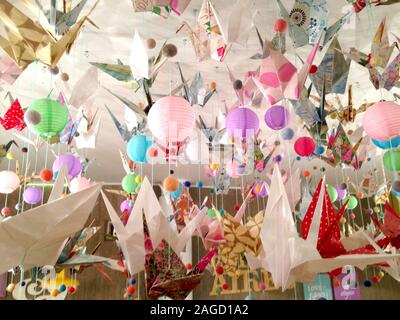 Colorful image of paper lamps and origami seagulls hanging from a white ceiling Stock Photo