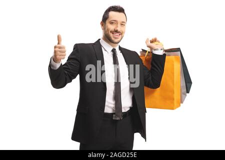 Handsome man in a suit and tie carrying shopping bags and showing thumbs up isolated on white background Stock Photo