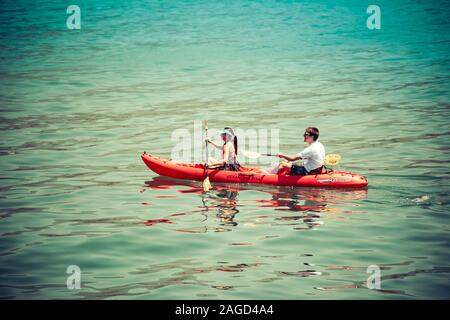 A young couple enjoy a leisurely paddle in an orange kayak in the Pacific Ocean, off  the coast of Santa Barbara, CA Stock Photo