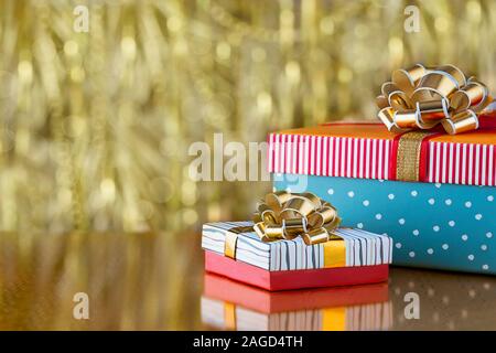Two gift boxes with bows on a gold blurred background. Holiday concept with copy spase. Stock Photo
