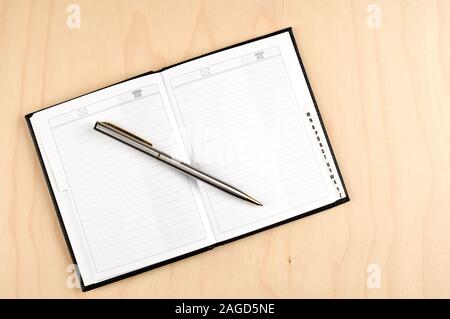 Address book and ballpoint pen on wooden table. Stock Photo