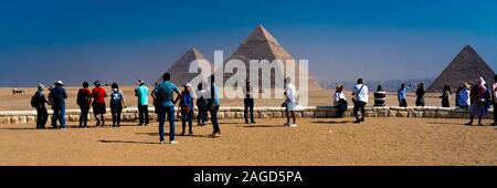 NOVEMBER 2019, CAIRO EGYPT, Camel in front of Great Pyramids of Giza, Cairo with tourists Stock Photo