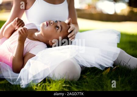 Young girl and her mother wearing ballet apparel relaxing on a grassy lawn Stock Photo