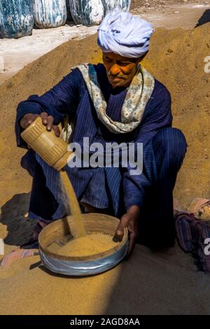 November 2019, EGYPT - Moslem Man Egypt in traditional clothing pours sand into bowl, Luxor Temple, Egypt Stock Photo