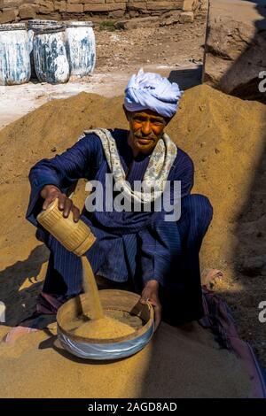 November 2019, EGYPT - Moslem Man Egypt in traditional clothing pours sand into bowl, Luxor Temple, Egypt Stock Photo