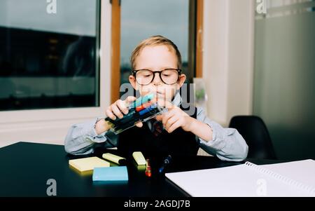 young boy working in an office with his dad helping him with his pens