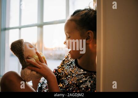 young girl laughing with her toys playing at home in Sweden at sunset Stock Photo