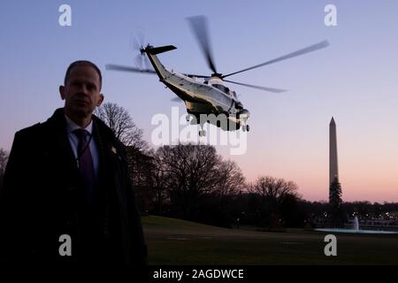A US Secret Service agent stands by as Marine One departs carrying US President Donald J. Trump en route to a rally in Michigan; on the South Lawn of the White House, in Washington, DC, USA, 18 December 2019. The US House of Representatives is poised to vote on two articles of impeachment against US President Donald J. Trump, for abuse of power and obstruction of Congress. If passed, Trump would become the third US president in history to be impeached. An impeachment would lead to a trial in the US Senate, where a two-thirds vote of approval would be necessary in order to remove Trump as presi Stock Photo