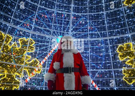 Valletta, Malta. 18th Dec, 2019. A man dressed as Santa Claus stands in front of colorful Christmas lights in Valletta, Malta, on Dec. 18, 2019. Colorful Christmas lights are seen in Valletta recently for the holiday season. Credit: Jonathan Borg/Xinhua/Alamy Live News Stock Photo