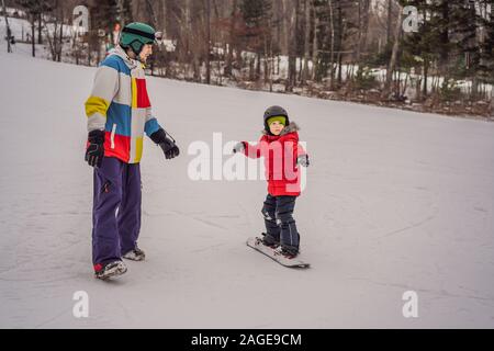 Snowboard instructor teaches a boy to snowboarding. Activities for children in winter. Children's winter sport. Lifestyle Stock Photo