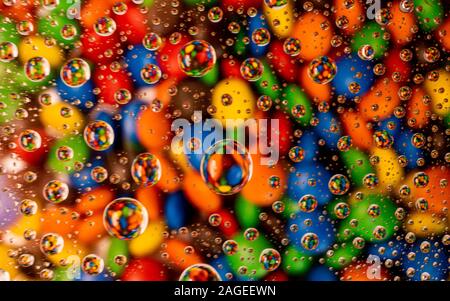 Cool background of colorful sweet candy under the glass covered with water drops Stock Photo