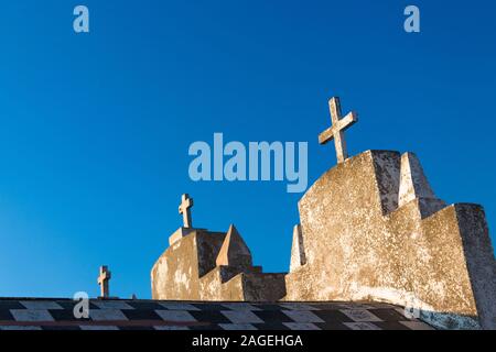 Three Stone christian crosses on the top of burial vaults in the seaside cemetery of Bonifacio, Corsica - blue sky in the background Stock Photo