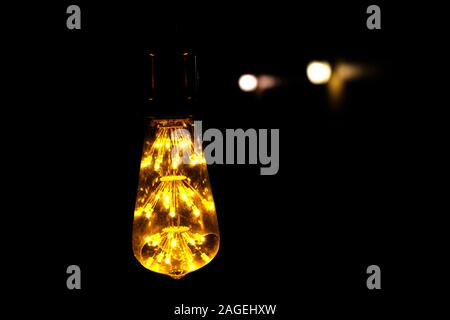 Classic retro incandescent led electric lamp warm white on black background, Vintage light bulb Stock Photo