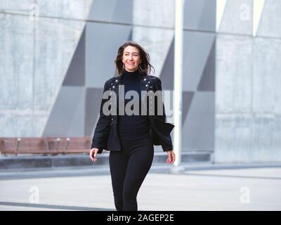 Woman in black suit walking in city Stock Photo