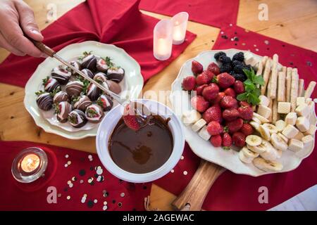 overhead view of hand dipping strawberry in chocolate fondue Stock Photo
