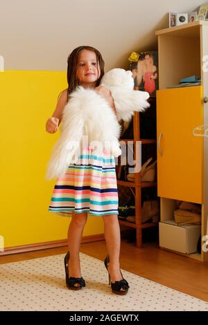 Little girl tries on high heels at home Stock Photo