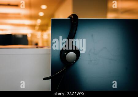 headset sitting on a computer at a desk in an office Stock Photo