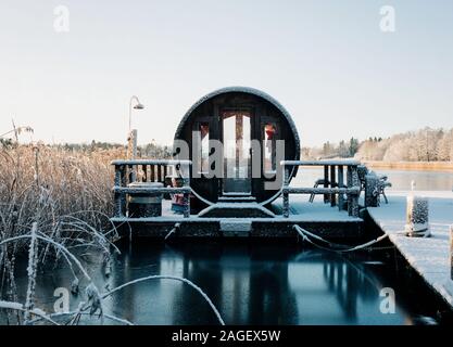 wooden sauna on a jetty covered in snow on a lake at sunset in Sweden Stock Photo