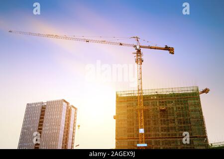 Construction site, silhouettes of construction industry workers on scaffolding against the sunset light. Stock Photo